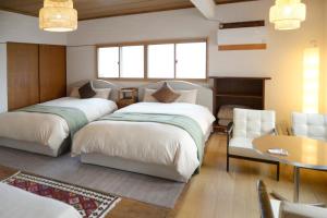 two beds in a room with a table and chairs at 宇都宮ゲストハウス花ニ嵐 Guesthouse Hana ni Arashi in Utsunomiya