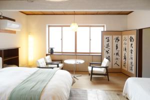 ein Schlafzimmer mit einem Bett, einem Tisch und Stühlen in der Unterkunft 宇都宮ゲストハウス花ニ嵐 in Utsunomiya