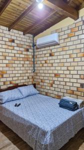 Un dormitorio con una cama en una pared de ladrillos. en Suíte família SOL & LUA Guarda do Embaú SC, en Guarda do Embaú