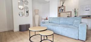 un soggiorno con divano blu e 2 tavoli di Le Charme du Sanctuaire 8 couchages 400m de la Grotte a Lourdes