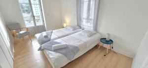 una camera con due letti e una sedia e due finestre di Le Charme du Sanctuaire 8 couchages 400m de la Grotte a Lourdes