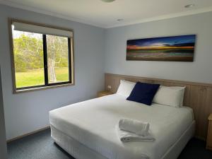 a bedroom with a white bed with a window at BIG4 Ulladulla Beachside Holiday Park in Ulladulla