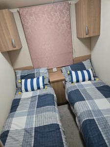 twee bedden in een kleine kamer met kasten bij Leas Happy Haven in Goswick Station