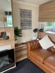 a living room with a leather couch and a window at Castle Lakes 60 - Wifi Included in Goswick Station +25 photos