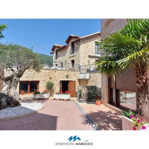 un gran edificio de piedra con una palmera delante de él en Aparthotel Marouco, en A Guarda