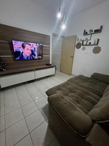 ein Wohnzimmer mit Sofa und Flachbildfernseher in der Unterkunft Casa aconchegante na Vila Tupi - Perto da Praia in Praia Grande