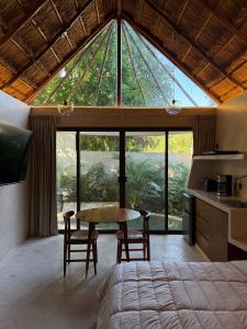 a room with a table and chairs and a large window at Aldea 58, cabañas de lujo con piscina en Merida centro in Azcorra
