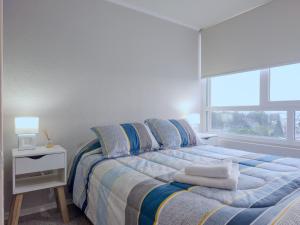 een slaapkamer met een bed met blauwe lakens en een raam bij Apart Total Temuco Centro in Temuco