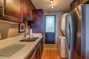 een keuken met houten kasten en een roestvrijstalen koelkast bij Lauloa 102 in Wailuku +19 foto's