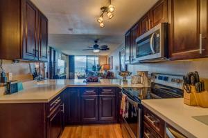 een grote keuken met houten kasten en een groot raam bij Lauloa 102 in Wailuku