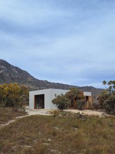 a white building in the middle of a field at Chalé Corumbau - Lapinha da Serra in Santana do Riacho