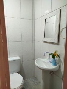 a white bathroom with a toilet and a sink at Casa Laurus in São Sebastião