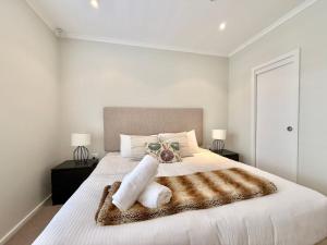 1 dormitorio con 1 cama blanca grande con manta marrón en Coastal Breeze at Caves Beach Villas, en Caves Beach 28 fotos más