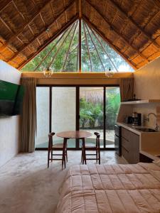 a bedroom with a bed and a table with chairs at Aldea 58, cabañas de lujo con piscina en Merida centro in Azcorra