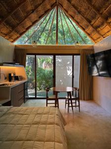 a bedroom with a bed and a table in front of a window at Aldea 58, cabañas de lujo con piscina en Merida centro in Azcorra +41 photos