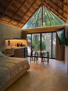 a bedroom with a bed and a kitchen with a table at Aldea 58, cabañas de lujo con piscina en Merida centro in Azcorra