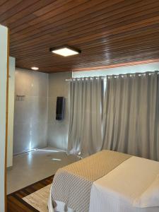 a bedroom with a bed and a shower with curtains at Chalé Corumbau - Lapinha da Serra in Santana do Riacho