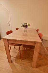 ein Holztisch mit einer Vase mit Blumen darauf in der Unterkunft Rez de chaussée appartement à Tournus - RIMA in Tournus
