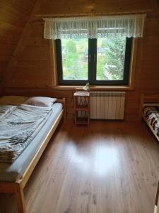 ein Schlafzimmer mit einem Bett und einem Fenster in einer Hütte in der Unterkunft Hacjenda - Apartamenty i Pokoje Gościnne in Czarna Góra + 76 Fotos
