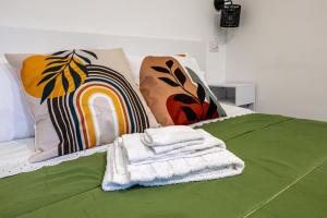ein grünes Bett mit einem Haufen Handtücher drauf in der Unterkunft Supernova House in Aranova