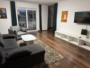 een woonkamer met een bank en een tv bij Westerwald Apartments - Das große Ferienhaus, zentral und ruhig, einfach gut! in Heiligenroth