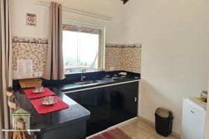 a kitchen with black counters and a sink and a window at Chalés Vale dos Pássaros Refúgio nas montanhas in Paraty