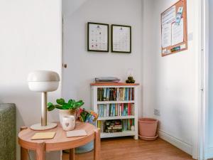 een woonkamer met een tafel en een boekenplank bij Cygnet Cottage in Warkworth