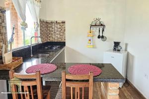 a kitchen with a table with chairs and a sink at Chalés Vale dos Pássaros Refúgio nas montanhas in Paraty +24 photos