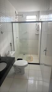 a white bathroom with a toilet and a sink at Praia de Guaibim in Valença