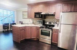 Una cocina con gabinetes de madera y un refrigerador de acero inoxidable. en White Rose House, en White Rock