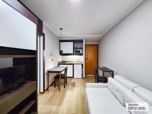 Una sala de estar con un sofá blanco y una cocina. en Triângulo Apart Hotel, en Vitória