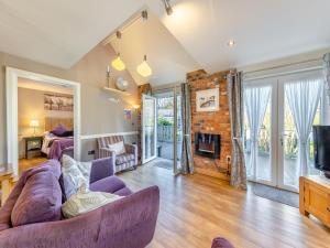 een woonkamer met een paarse bank en een open haard bij Ty Teiliwr - Uk45719 in Brynteg