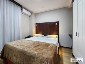 Un dormitorio con una cama grande con cabecero de madera. en Triângulo Apart Hotel, en Vitória 42 fotos más