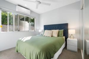 een slaapkamer met een bed met een blauw hoofdeinde en een raam bij Golden Valley Luxury Hinterland Escape in Valdora +17 foto's