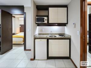 Una pequeña cocina con fregadero y microondas. en Triângulo Apart Hotel, en Vitória