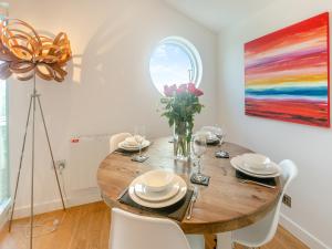 un comedor con una mesa de madera y una pintura en Una Aurum 57, en Carbis Bay