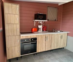 a kitchen with wooden cabinets and a sink and a microwave at Le Tomaflo in Le Marin