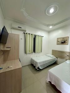a hotel room with two beds and a television at Hotel Luci in Terra Santa