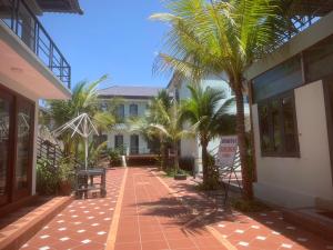 une cour avec des palmiers devant un immeuble dans l'établissement Salt & Wind Living - Phan Rang Beachfront, à Bắc Sớn