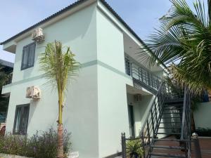 une maison blanche avec un palmier devant dans l'établissement Salt & Wind Living - Phan Rang Beachfront, à Bắc Sớn 1 autre photo