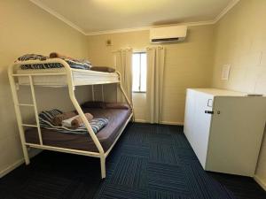 une petite chambre avec deux lits superposés et un réfrigérateur dans l'établissement Ningaloo Club Backpackers, à Coral Bay