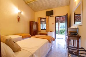 een slaapkamer met twee bedden en een televisie bij Pousada das Cavernas in Iporanga