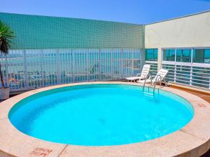 una gran piscina con 2 sillas y un edificio en Triângulo Apart Hotel, en Vitória