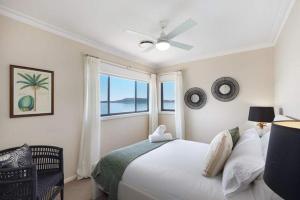 a white bedroom with a bed and a window at Waters Edge by Coast Hosting in Koolewong