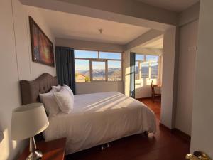 a bedroom with a white bed and a window at Departamento con Vista a la Ciudad in Cusco
