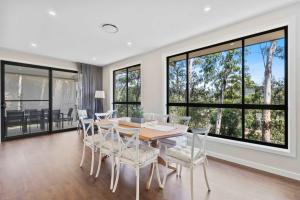 a dining room with a table and chairs and large windows at Ruby Lodge by Coast Hosting in Green Point