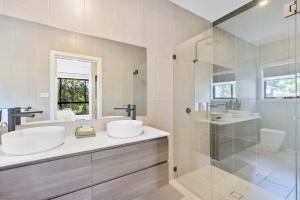 a white bathroom with two sinks and a shower at Ruby Lodge by Coast Hosting in Green Point