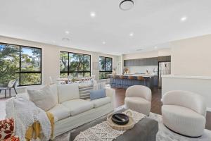 a living room with a white couch and a kitchen at Ruby Lodge by Coast Hosting in Green Point +15 photos
