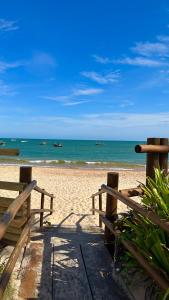 a beach with two wooden benches and the ocean at Alugo apartamento em Guarajuba, e para réveillon! in Camaçari
