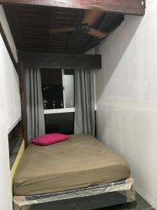 een klein bed in een kamer met een raam bij Pousada Recanto da Prainha in São Vicente